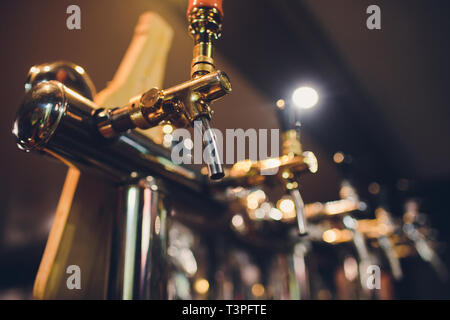 Die Theke mit Flaschen und Vorrichtung zum Dosieren von Bier. Vorrichtung zum Dosieren von Bier an der Bar. Pub. Die Bar im Restaurant. Geräte Stockfoto