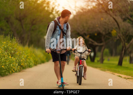 Papa mit Kindern auf Rollern Stockfoto