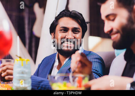 Zwei Mann in Bar halten Gläser Sitzen an der Theke, Trinken Cocktail, fröhliche Freunde treffen Bar zu sprechen. Stockfoto