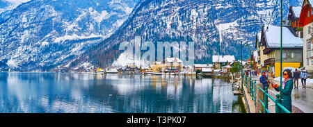 HALLSTATT, Österreich - 21. FEBRUAR 2019: Genießen Sie die malerischen Hallstätter siehe und schneebedeckten Dachstein Alpen von der Uferpromenade des Seestraße, auf Februa Stockfoto