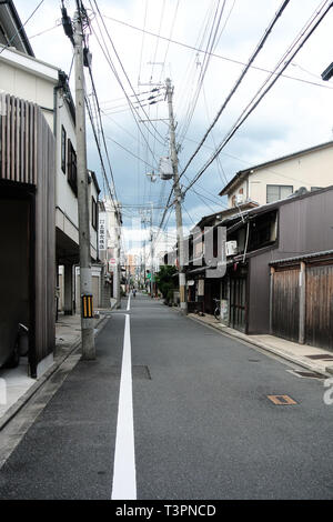 Schmale ländlichen Straße in der Stadt Kyoto mit alten traditionellen japanischen Gebäude aus Holz und krummen Strommasten Stockfoto