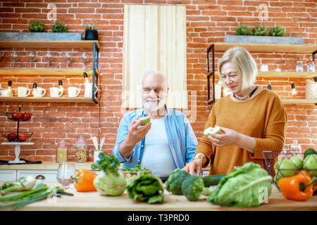 Freundliche senior Paar Obst essen gemeinsam mit gesunden Lebensmitteln in der Küche zu Hause. Konzept der gesunden Ernährung im Alter Stockfoto