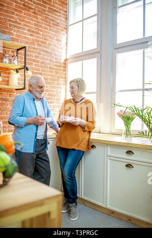 Senior Paar einen Kaffee Zeit, gemeinsam in der Nähe der Fenster in der Küche zu Hause. Stockfoto