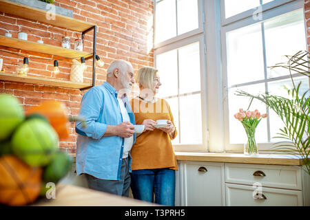 Senior Paar einen Kaffee Zeit, gemeinsam in der Nähe der Fenster in der Küche zu Hause. Stockfoto