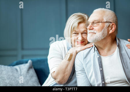 Porträt einer wunderschönen senior Paar einander umarmen, sitzen auf der Couch zu Hause Stockfoto