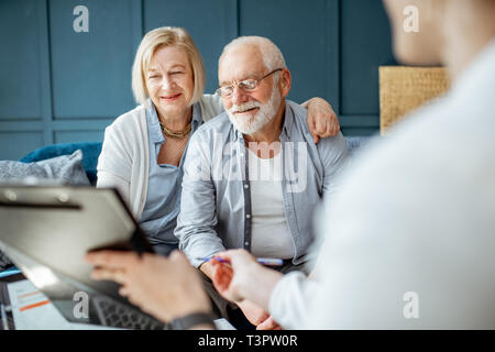Gerne Älteres Paar beim Treffen mit Agenten oder finanzieller Berater, Unterzeichnung einiger Abkommen in der komfortablen Büro Stockfoto