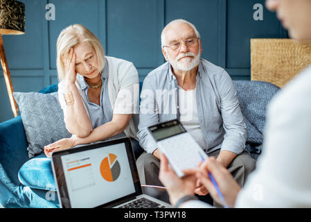 Senior Paar mit traurigen Emotionen während des Treffens mit finanzieller Berater, Unterzeichnung einiger Abkommen im Büro Stockfoto