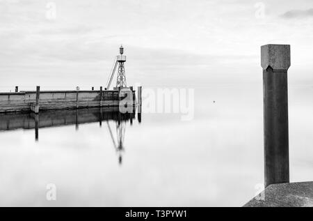 Der Hafen Mole in Rorschach Hafen auf einem typischen April Frühling Morgen am Bodensee in der Schweiz. Lange Belichtung mit vielen negativen Raum. Stockfoto