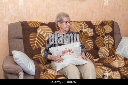 Über 80 Jahre alte Großmutter sitzt auf einer Couch Stockfoto