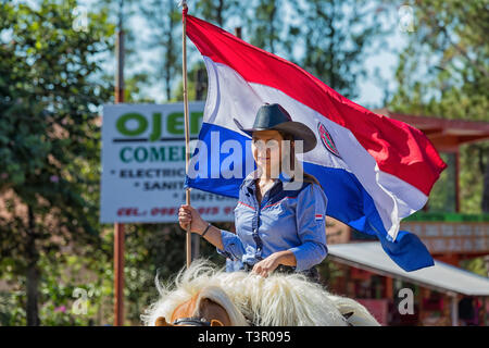 Eine schöne Frau stolz reitet ihr Pferd mit Paraguayischen Flagge während der jährlichen paraguayischen Independence Day Parade. Stockfoto