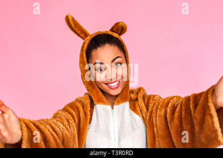 Junge Frau in Bunny kigurumi steht auf rosa Hintergrund Hände mit isolierter offener suchen Kamera lächelt freundlich close-up Stockfoto