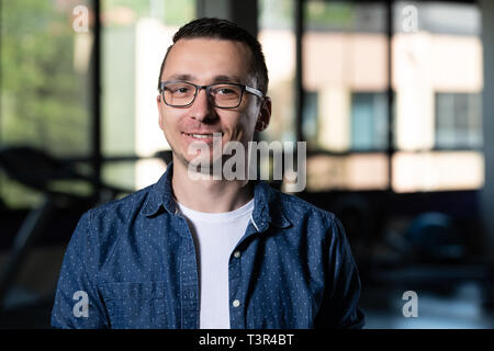 Portrait von schwachen Kerl Nerd mit Brille im Fitnesscenter Fitnesscenter stehen Starke Stockfoto