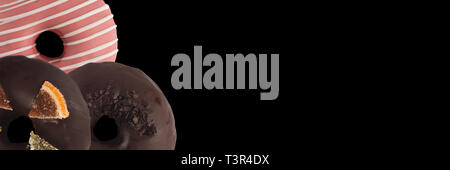 Drei verschiedenen Donuts auf schwarzem Hintergrund. Schließen sie isoliert. Banner. Stockfoto