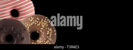 Drei verschiedenen Donuts auf schwarzem Hintergrund. Schließen sie isoliert. Banner. Stockfoto