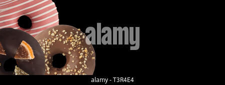 Drei verschiedenen Donuts auf schwarzem Hintergrund. Schließen sie isoliert. Banner. Stockfoto