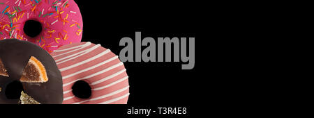 Drei verschiedenen Donuts auf schwarzem Hintergrund. Schließen sie isoliert. Banner. Stockfoto