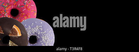 Drei verschiedenen Donuts auf schwarzem Hintergrund. Schließen sie isoliert. Banner. Stockfoto