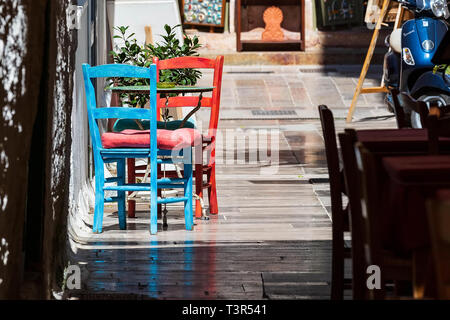 Nafplio, Griechenland Blick auf die Altstadt mit roten und blauen bunten Tisch und Stühlen in kleinen Street Cafe in Nafplion, Peloponnes Stockfoto