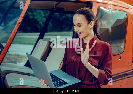Gut - Zufrieden aussehende Frau mit gebunden Haar winkte ihr Haar und Begrüßung Stockfoto