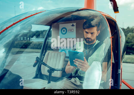 Aufmerksame ernsthafte Kerl mit schwarzen Sitzen bärtigen im Hubschrauber Stockfoto
