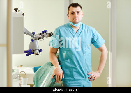 Ein männlicher Zahnarzt steht mit einem Mikroskop Stockfoto