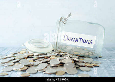 Münzen und Glas Glas mit Geld spenden Label, das Finanzkonzept. Stockfoto