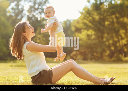 Mutter mit Kind spielen auf Gras bei Sonnenuntergang. Stockfoto