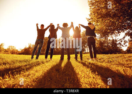 Personen stehend mit erhobenen Armen auf der Wiese Stockfoto