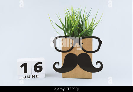 Fröhliches lustiges Gesicht mit Brille und Bart und Haare aus Gras und weißen Holzmöbeln block Kalender für 16. Juni zu feiern Vatertag Stockfoto