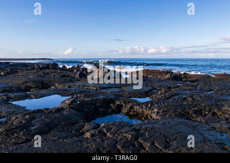 Rocky vulkanischen Küstenlinie bei Ebbe, in der Nähe von Kona, auf Hawaii Big Island. Meerwasser füllt Hohlräume in den Steinen. Stockfoto