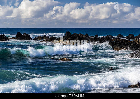 Wellen in Richtung Ufer in der Nähe von South Point, in der Hawaii Big Island rollen. Vulkanischen Felsen in der Brandung. Blauen Pazifischen Ozean erstreckt sich bis zum Horizont; overhe Stockfoto