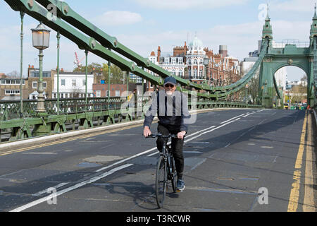 Mann mit dem grauen Bart Zyklen über eine leere Hammersmith Bridge, London, England, nach der Schließung aus Sicherheitsgründen der Themse Kreuzung Stockfoto