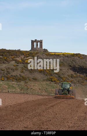 Ein Landwirt Eggen ein Feld unter dem War Memorial in der Nähe von Stonehaven in Aberdeenshire Stockfoto