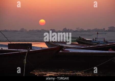 Sonnenaufgang auf dem Ganges. Boote für Touristen sind auf der Pier. Indien. Varanasi Stockfoto
