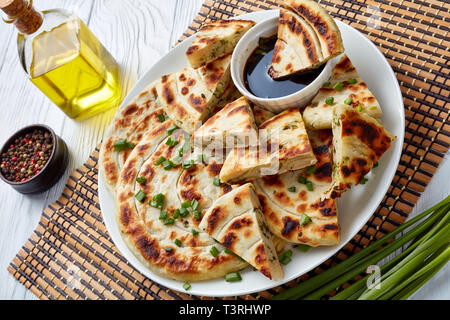 Hot chinesischen Frühlingszwiebel Pfannkuchen mit Soja Sauce auf einer Platte auf einem weißen Holz- Tabelle, Ansicht von oben, close-up Stockfoto