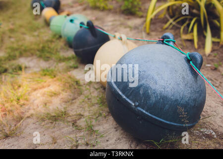 Lustiges Gesicht durch die Hand einer orange Boje in oben auf einem Felsen am Strand von einer Klippe. Gesicht, mit Augen und Mund und eine weiße Plastiktüte, Stockfoto