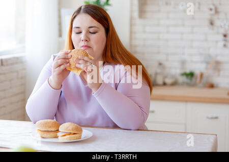 Angenehme nachdenkliche Frau suchen an der Burger Stockfoto