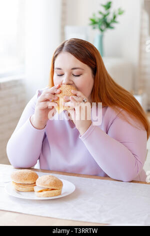 Schön mollig Frau essen eine leckere Burger Stockfoto