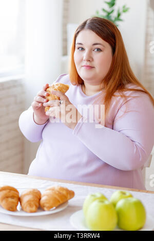 Schön mollig Frau mit ein leckeres Croissant Stockfoto