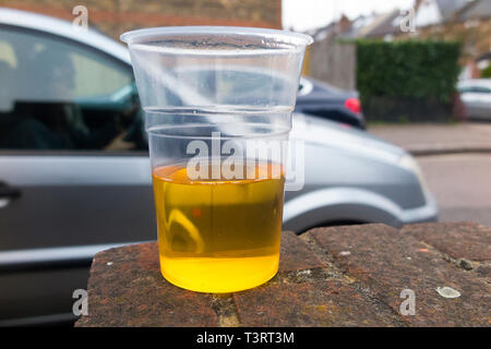 Fahrenden Autos fahren vorbei an einem halb leeren Kunststoffbecher Lager das Thema betrunken/trinken Fahrer zu illustrieren, und Fahren unter dem Einfluss von Alkohol. England UK (108) Stockfoto