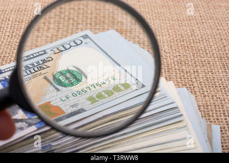 Lupe wird über die Banknote Bündel von US-Dollar gehalten. Stockfoto