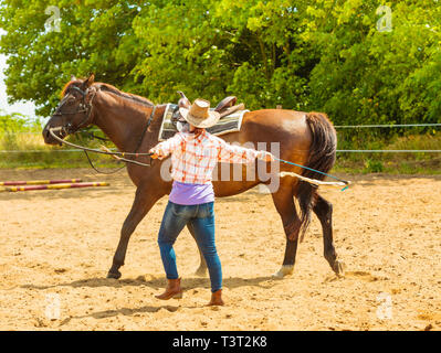 Aktive Frau in westlichen Cowgirl Hut mit Pferd. American Girl in der Landschaft Ranch. Stockfoto