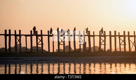 Menschen zu Fuß auf erhöhten Holzsteg bei Sonnenuntergang Stockfoto