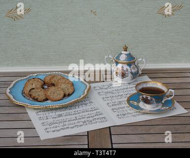 Englisch Teetasse mit Untertasse, Sugar Bowl und einem Kuchen Teller mit Keksen, Fine Bone China Porzellan, auf einem Blatt von Musik Stockfoto