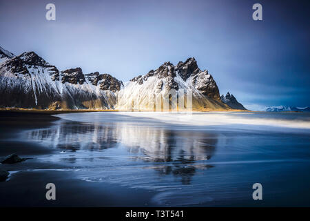 Ozean Wellen am Strand unter Snowy Mountains Stockfoto