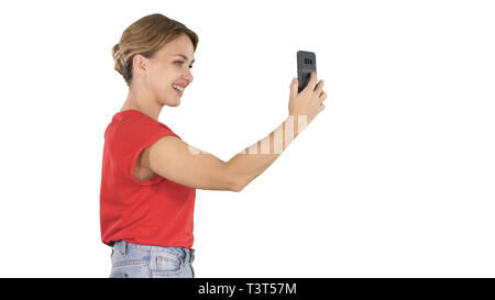 Schöne junge Frau zu Fuß und mit einem Smartphone Bilder und selfies auf weißem Hintergrund zu nehmen. Stockfoto