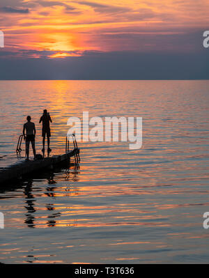 Zwei Männer zu fotografieren, um den Sonnenuntergang mit einem Ipad an einer Pier im Zentrum von Visby, Gotland, Schweden. Skandinavien Stockfoto