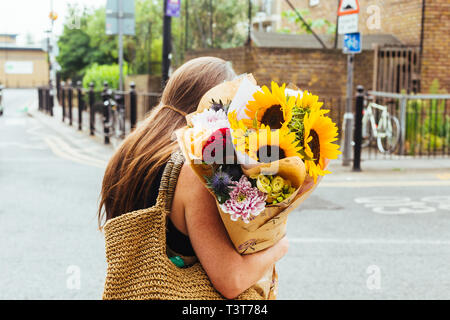 London/Großbritannien - 22. Juli 2018: Junge Frau mit Blumen auf der Columbia Road Blumenmarkt im Osten von London, Großbritannien erworben Stockfoto