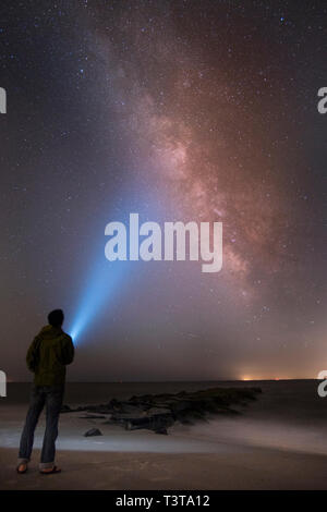 Asiatischer Mann leuchtende Taschenlampe am Sternenhimmel Stockfoto