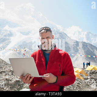 Mann mit Laptop auf verschneiten Bergen Stockfoto